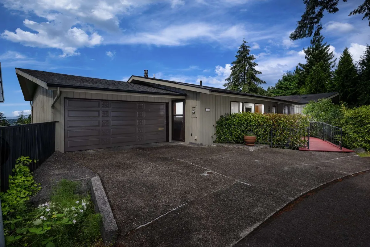 This exterior shot features the home's entrance pathway, the garage door, and is framed by abundant greenery. The inviting entry hints at easy access to outdoor adventures and a welcoming environment for arrivals with pets.