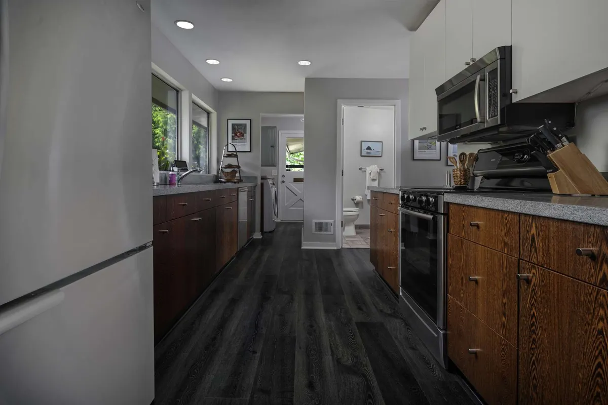A bright, inviting kitchen featuring stainless steel appliances, wooden cabinetry, granite countertops, and large windows that fill the space with natural light. The kitchen is designed for cooking and entertaining, with ample counter space and a warm, welcoming atmosphere.